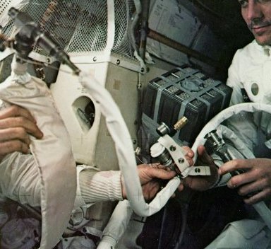 A photo of astronauts,Swigert and Haise,holding a hose