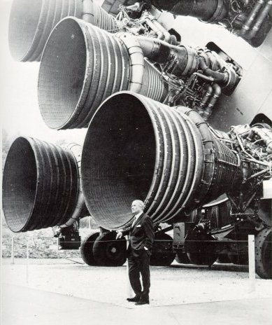 A photo of Dr. von Braun standing next to one of the five engines of Saturn V