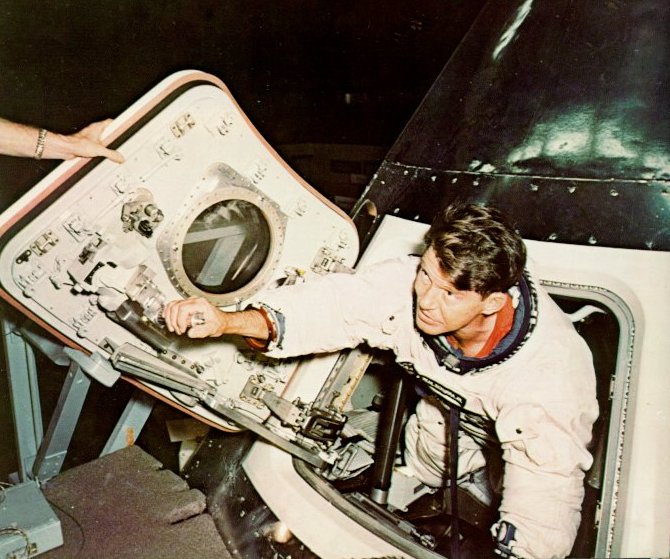 A photo of astronaut Wally Schirra inspecting the new hatch of the capsule